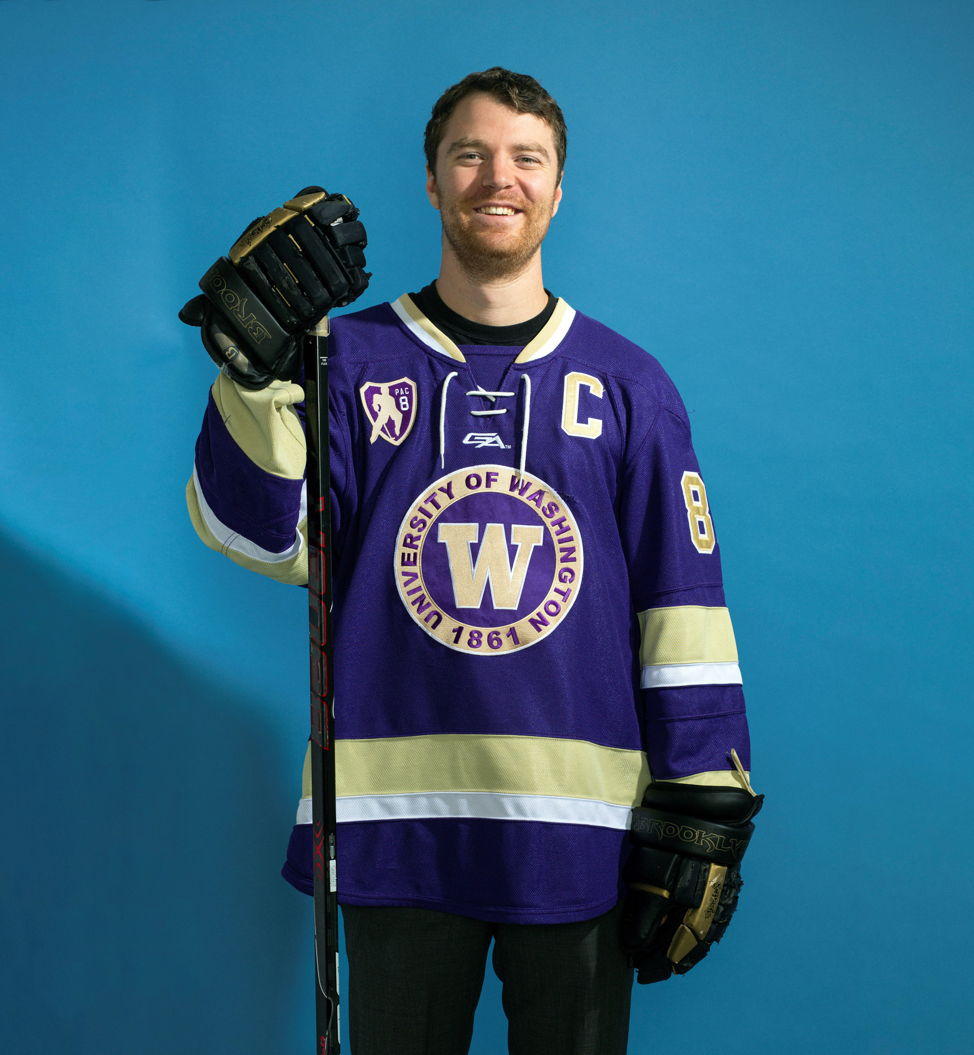 Ryan Minkoff smiles while wearing his UW Hockey Club uniform and holding a hockey stick