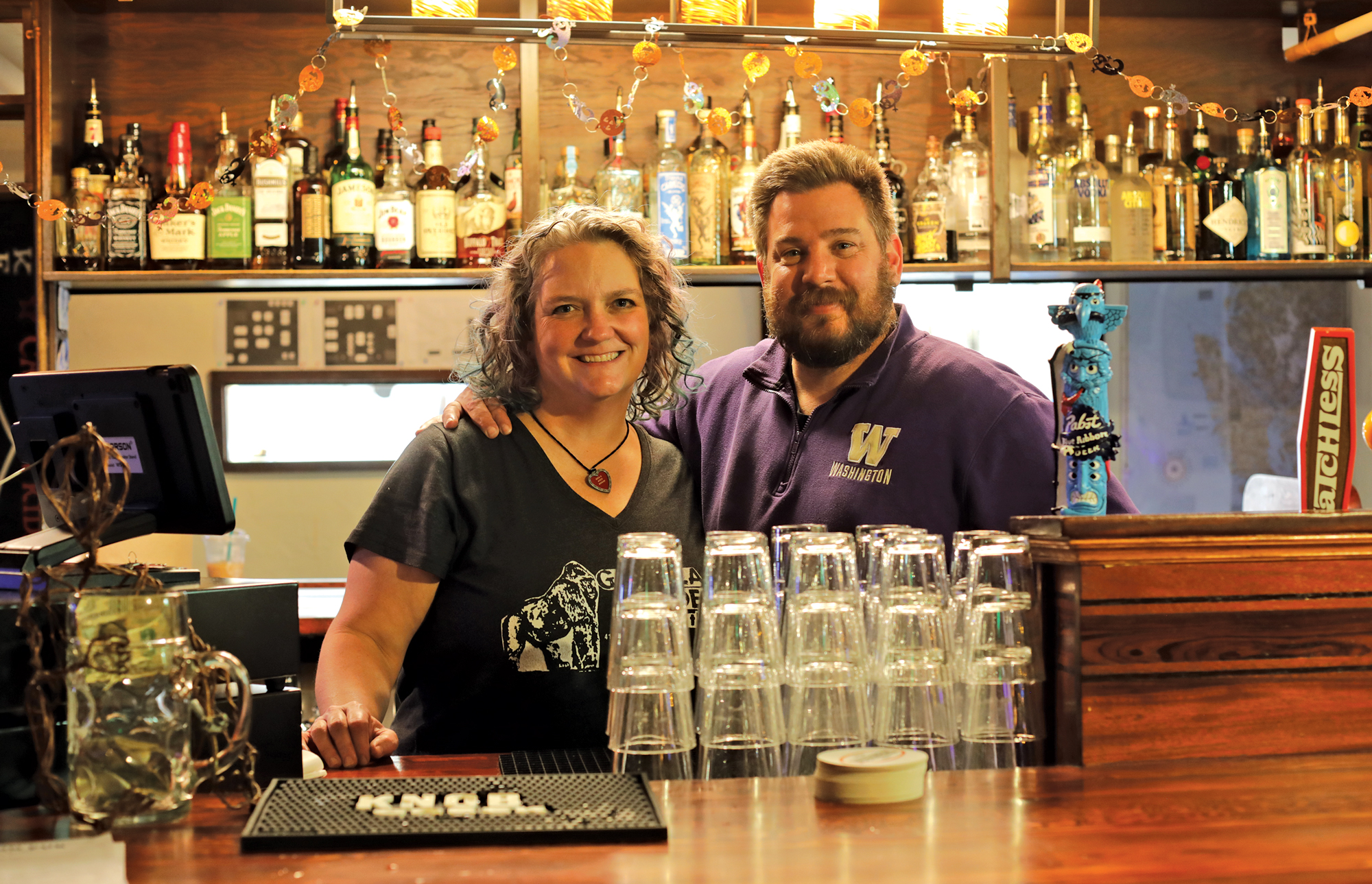 Jen Gonyer and Al Donahue smiling behind the College Inn bar