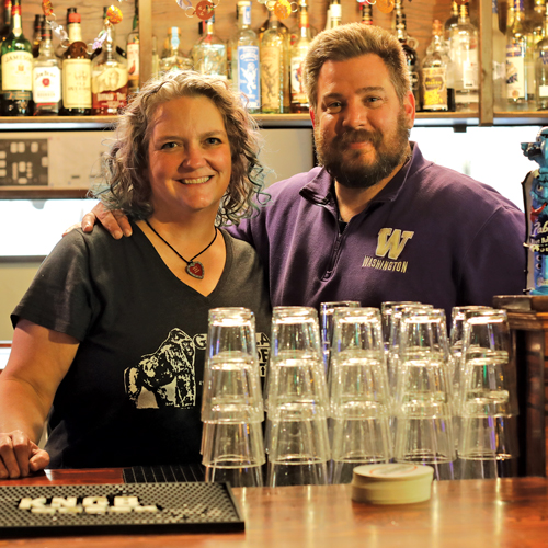 Jen Gonyer and Al Donahue smiling behind the College Inn bar