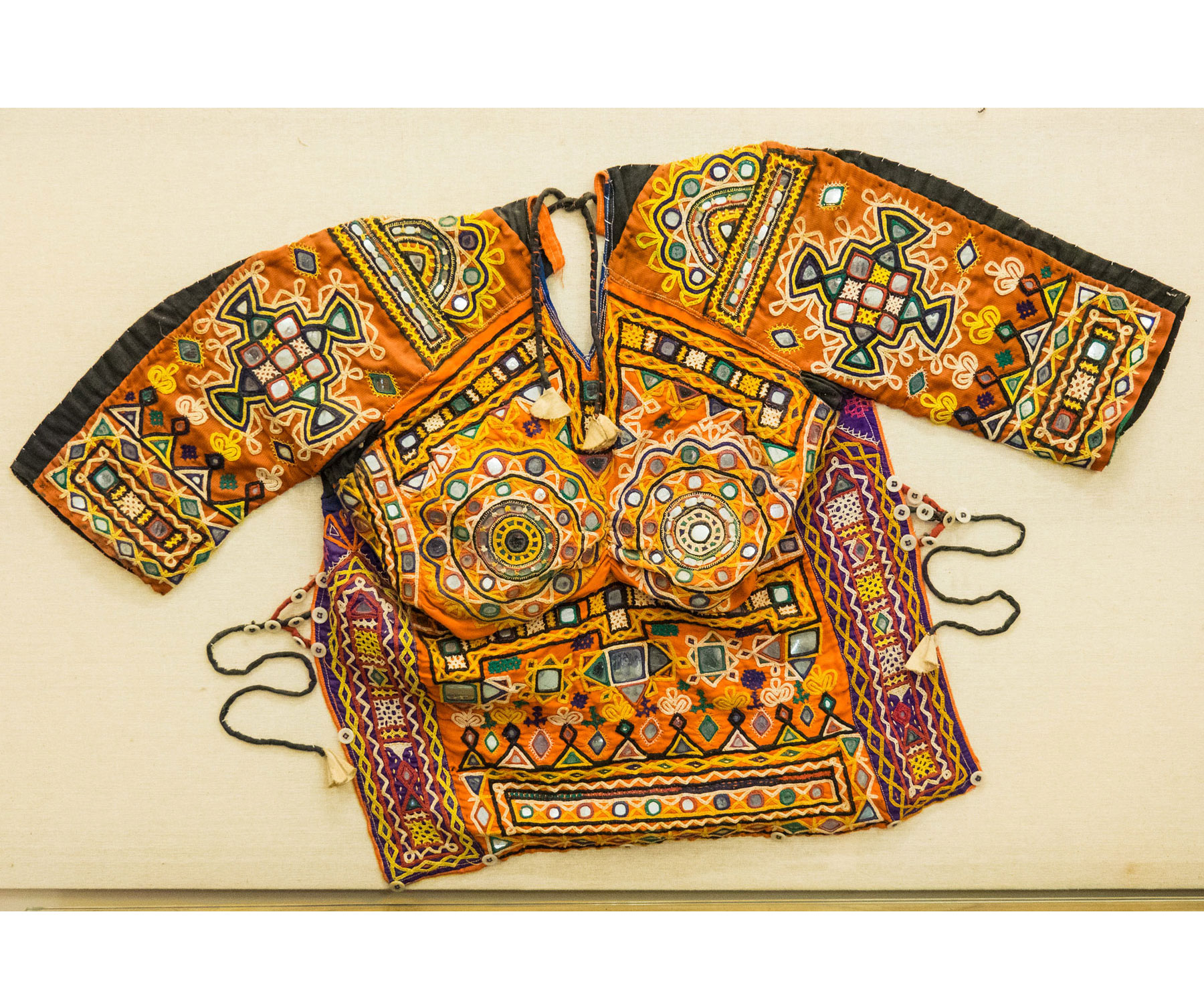 An orange shirt with many colors and decorations embroidered