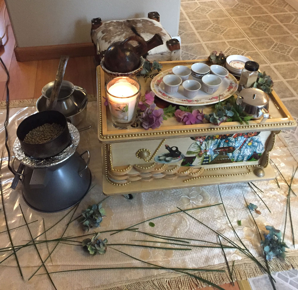 A small decorative table holds mugs, coffee and a lit candle.