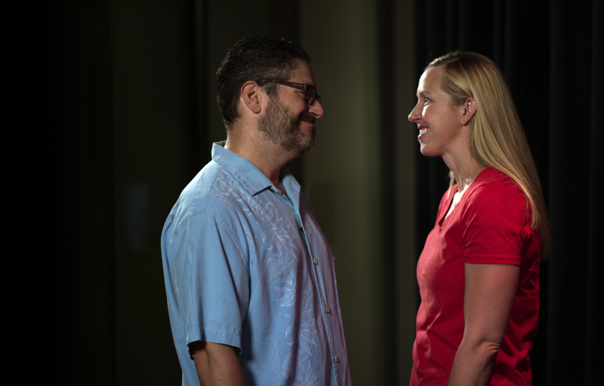 Still from a movie showing a man and woman smiling at each other backstage