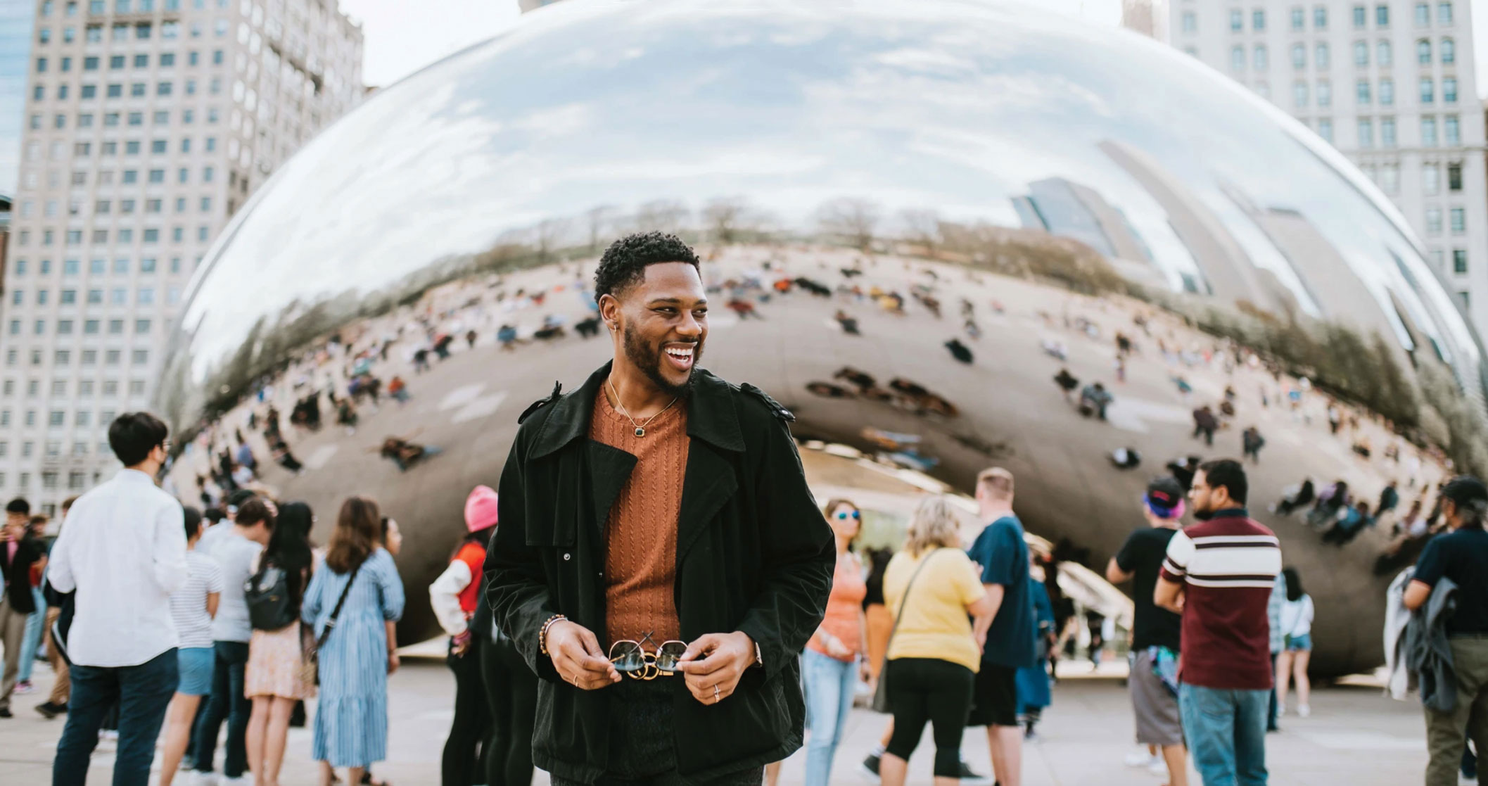 A stylish man smiles in front of the Chicago 
