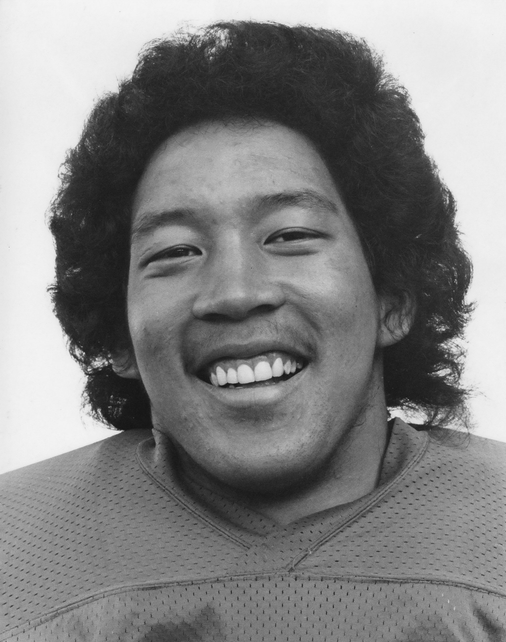 Black and white photograph of a man in a football uniform smiling