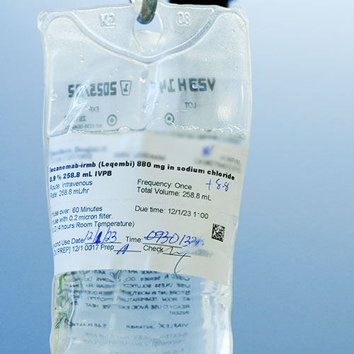 A medical bag with fluid is labeled "lecanemab" with patient information