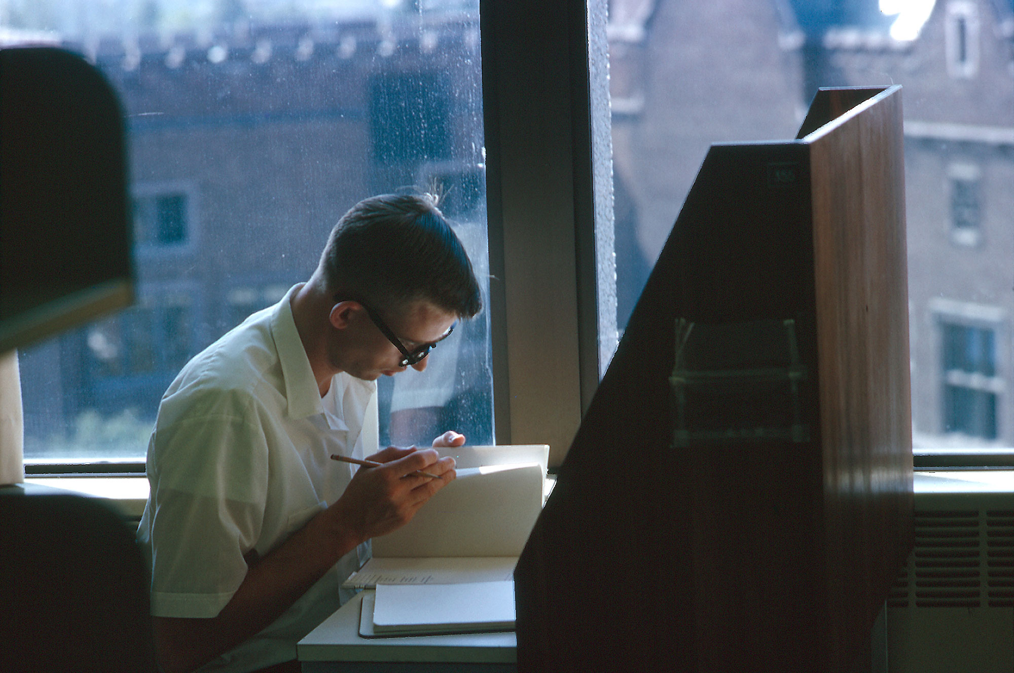 A 35mm photo from the UW archives by Mary Levin shows a student paging through a book in Allen Library.