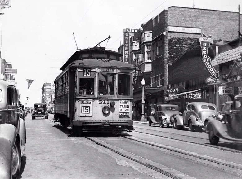 An old film photo shows a streetcar on the Ave next to the University Book Store.