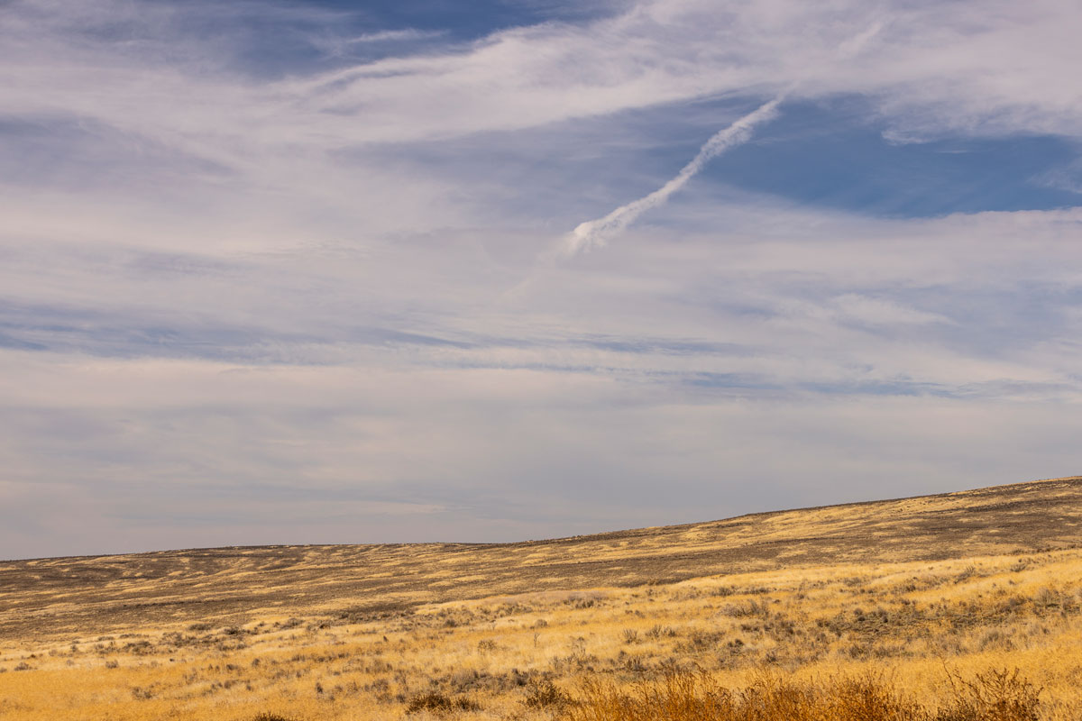 A wide expanse of land with cloudy blue skies