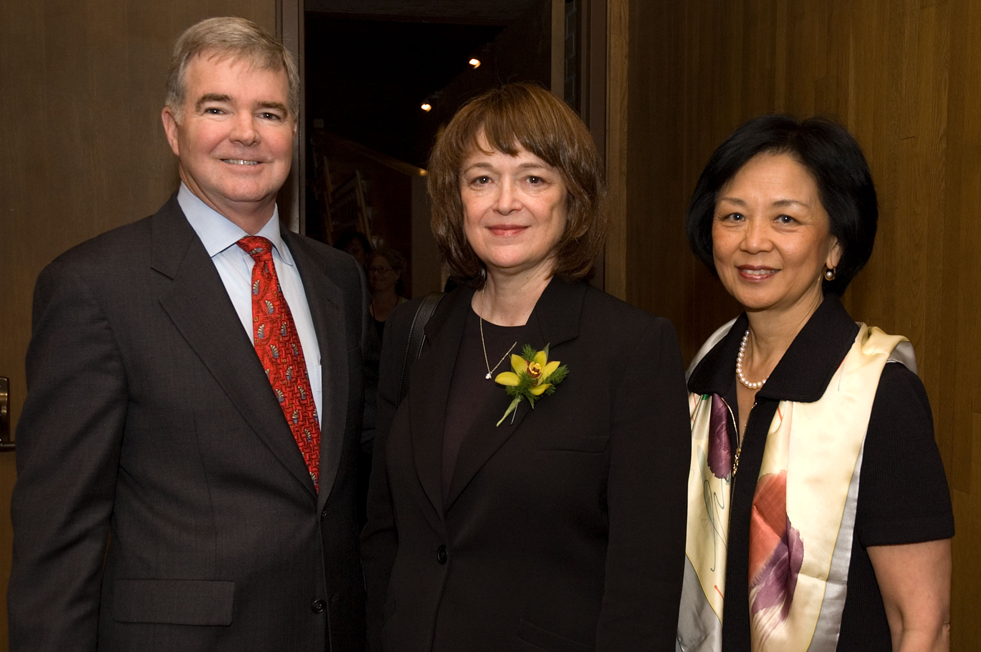 A man and two women stand in an event space smiling.