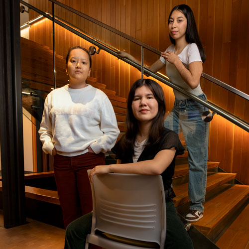 Three young women pose in a stairwell