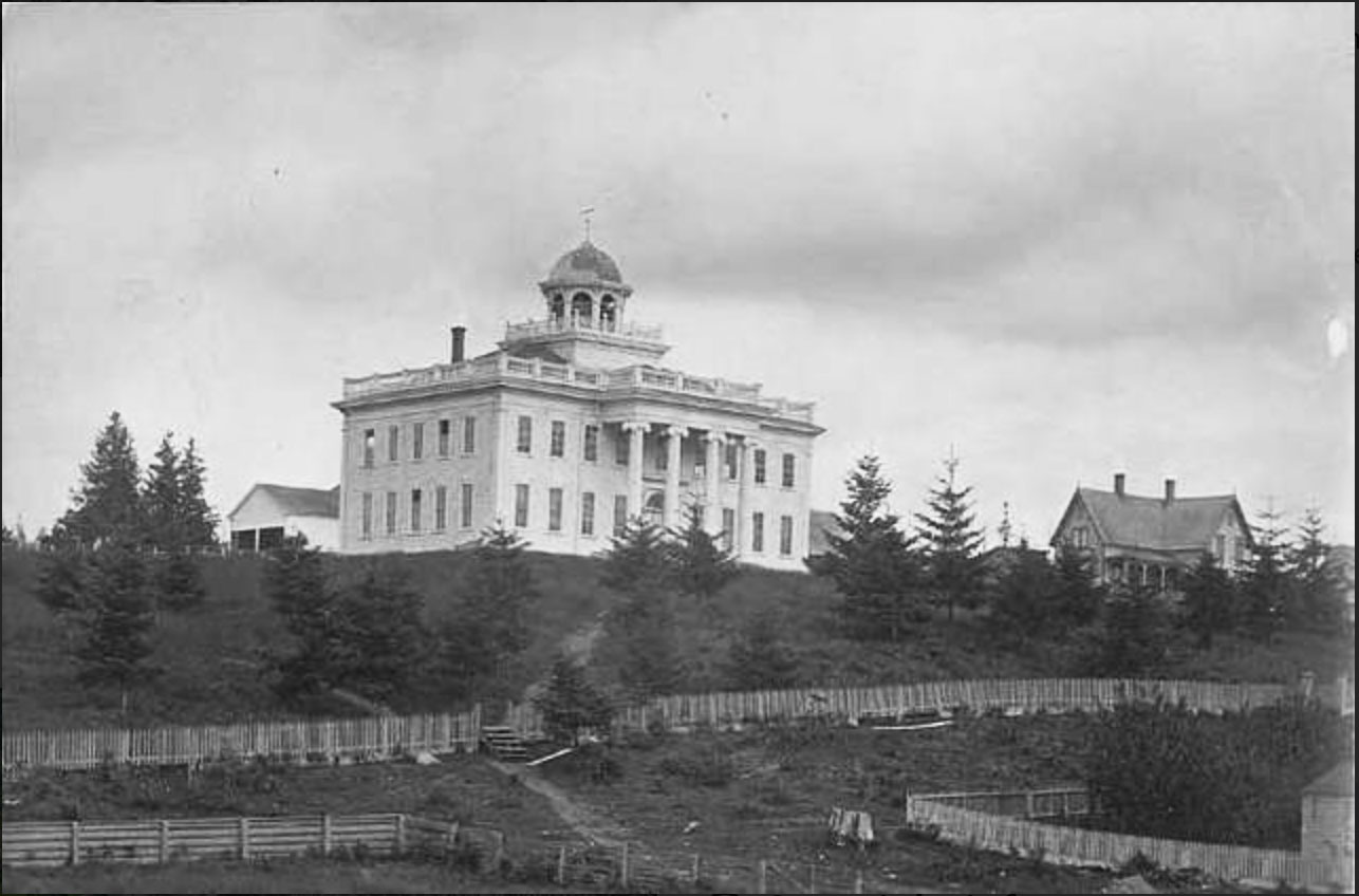 An old photo scan of a grand-looking white building on a hill