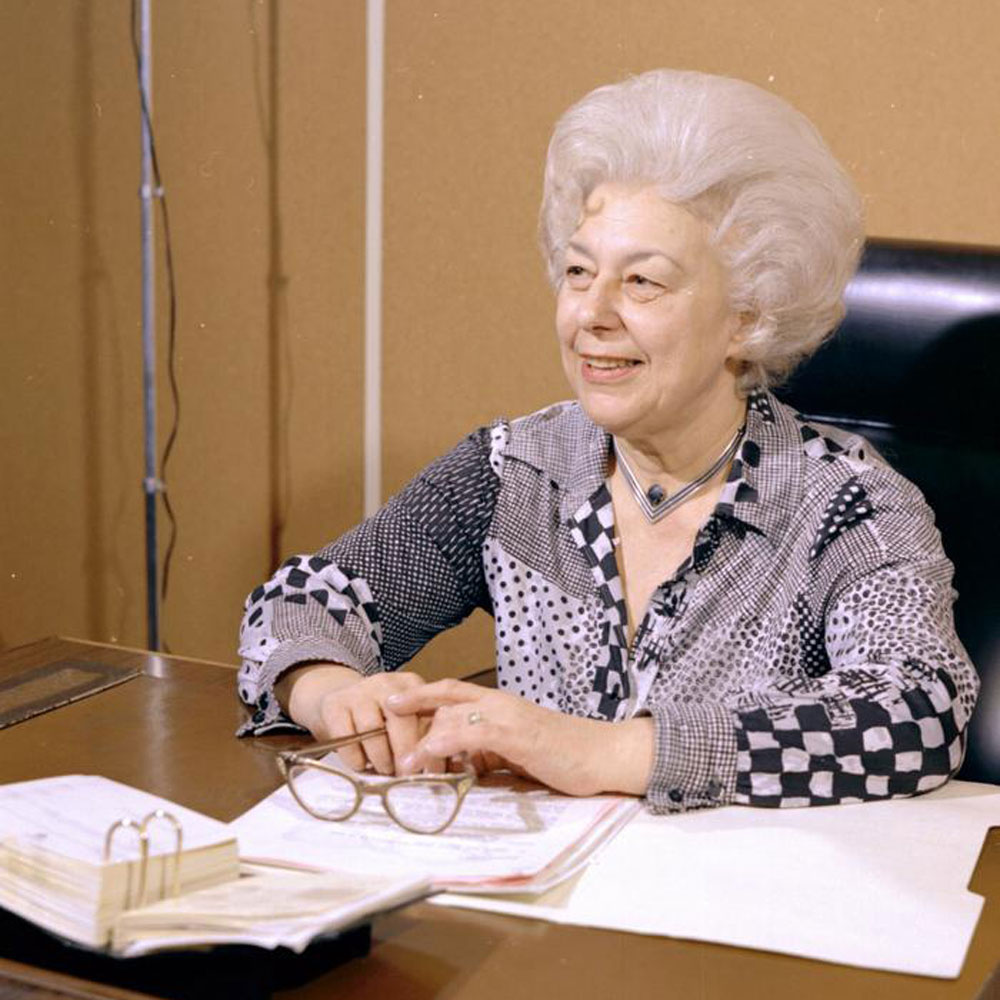 Jeanette Williams sits in the city council chamber wears a patterned shirt