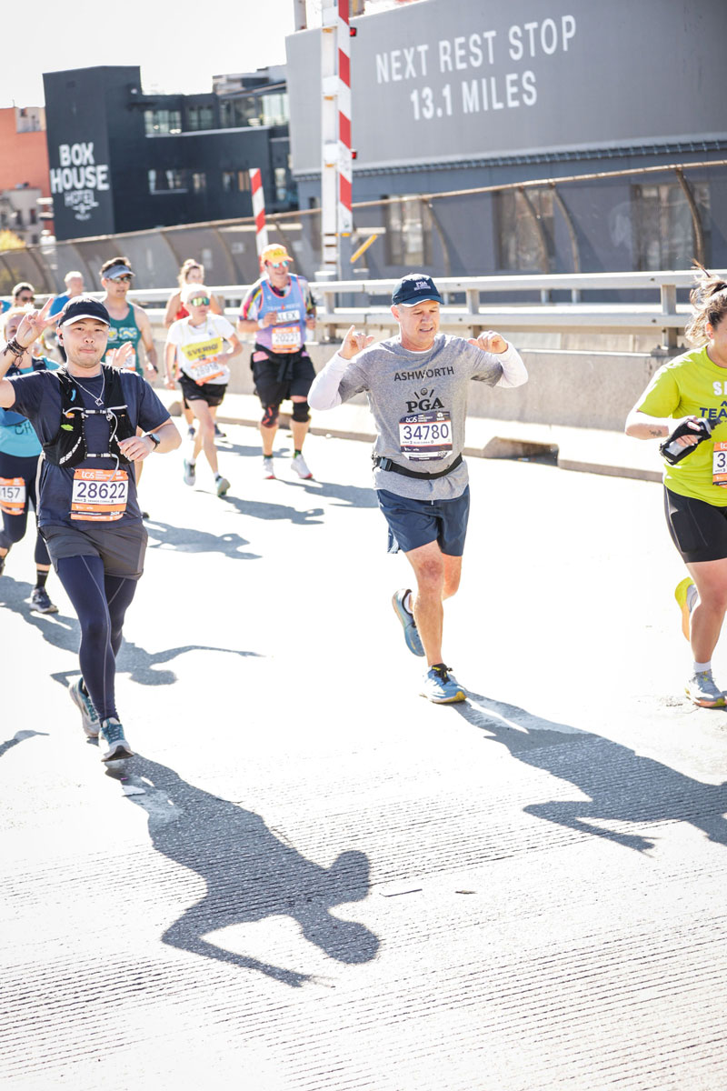 Scott Ashworth raises his arms in celebration as he runs the New York City Marathon.