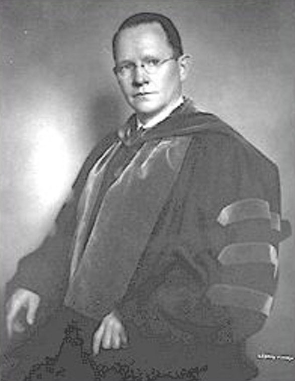 A very old photo of a man in academic regalia looking stern