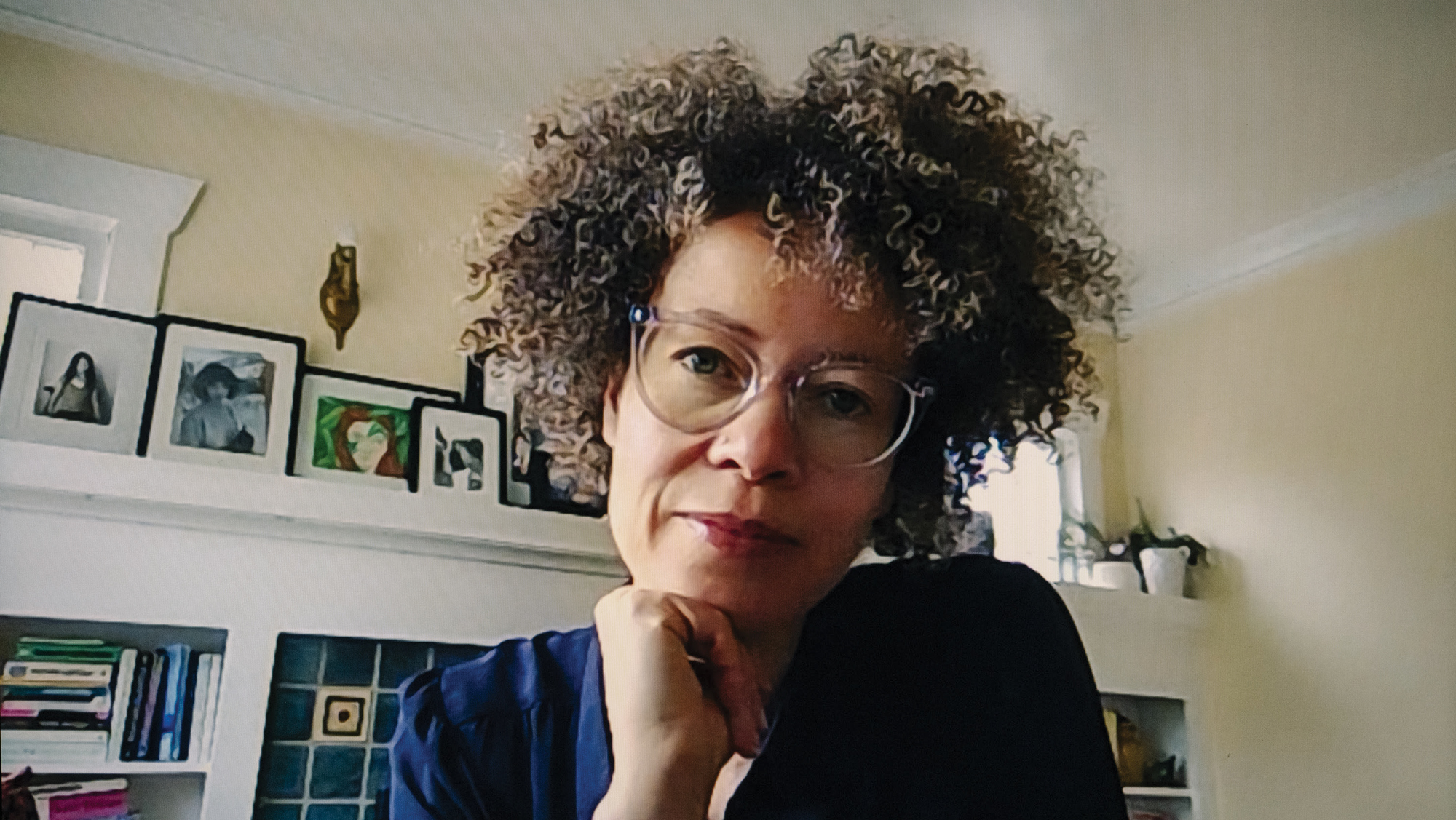 Wendy Barrington wears a dark blue shirt and clear glasses and rests her head on her chin while looking into the camera.