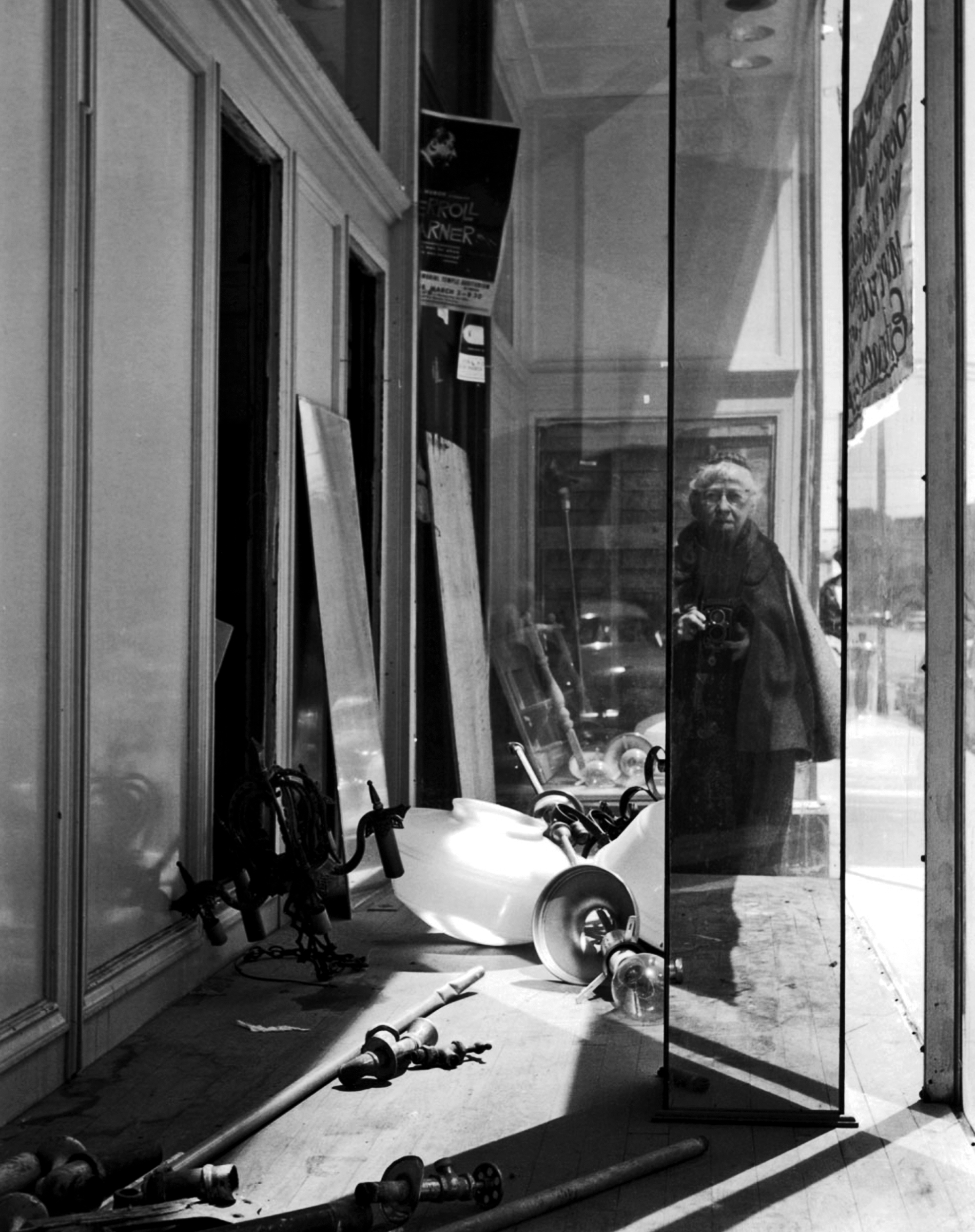Imogen Cunningham takes a black-and-white self portrait in a storefront window.