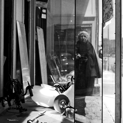 Imogen Cunningham takes a black-and-white self portrait in a storefront window.