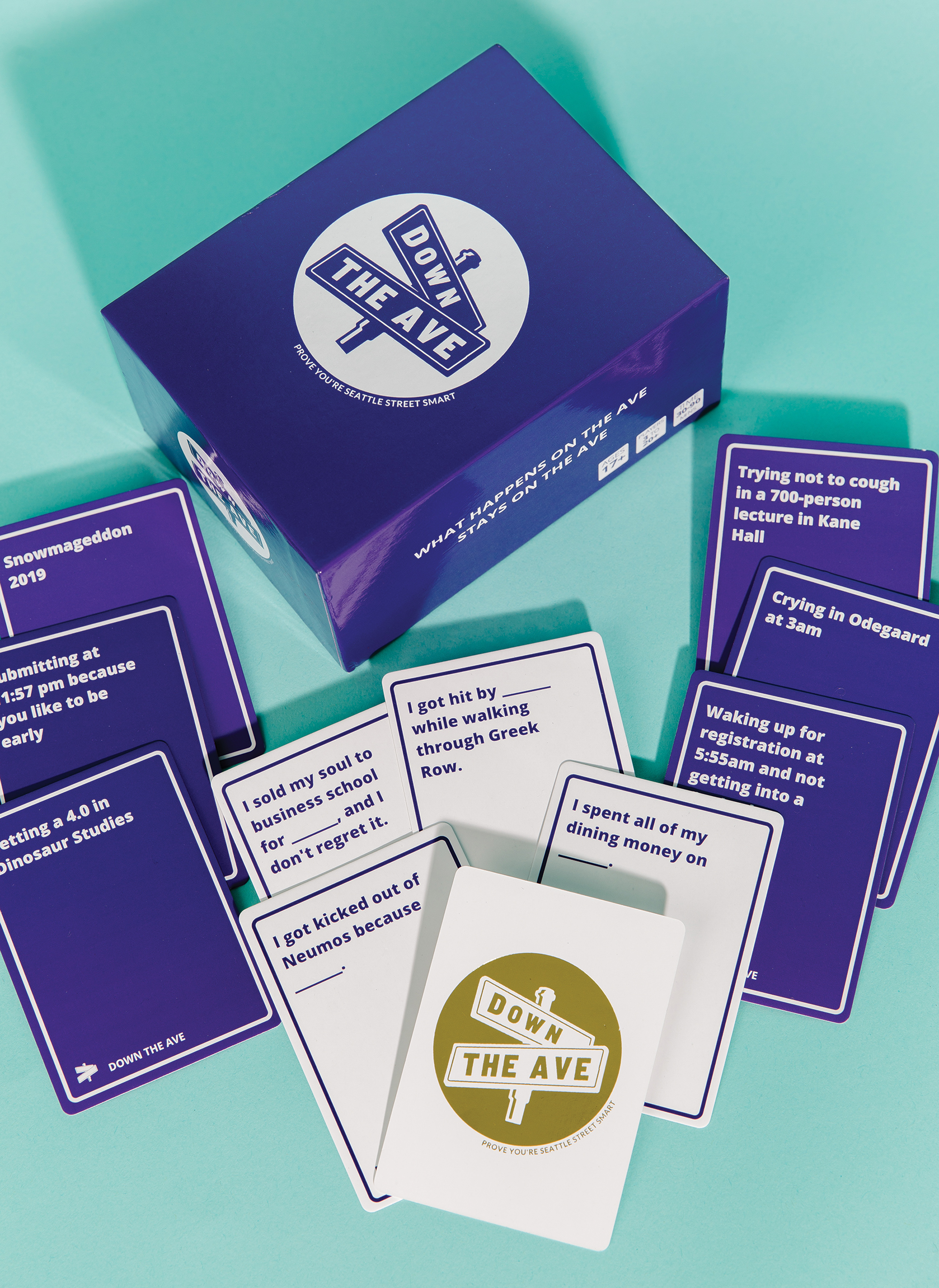 Down The Ave card game box on a table with game cards scattered around it