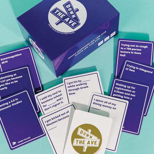 Down The Ave game box on a table with game cards scattered around it