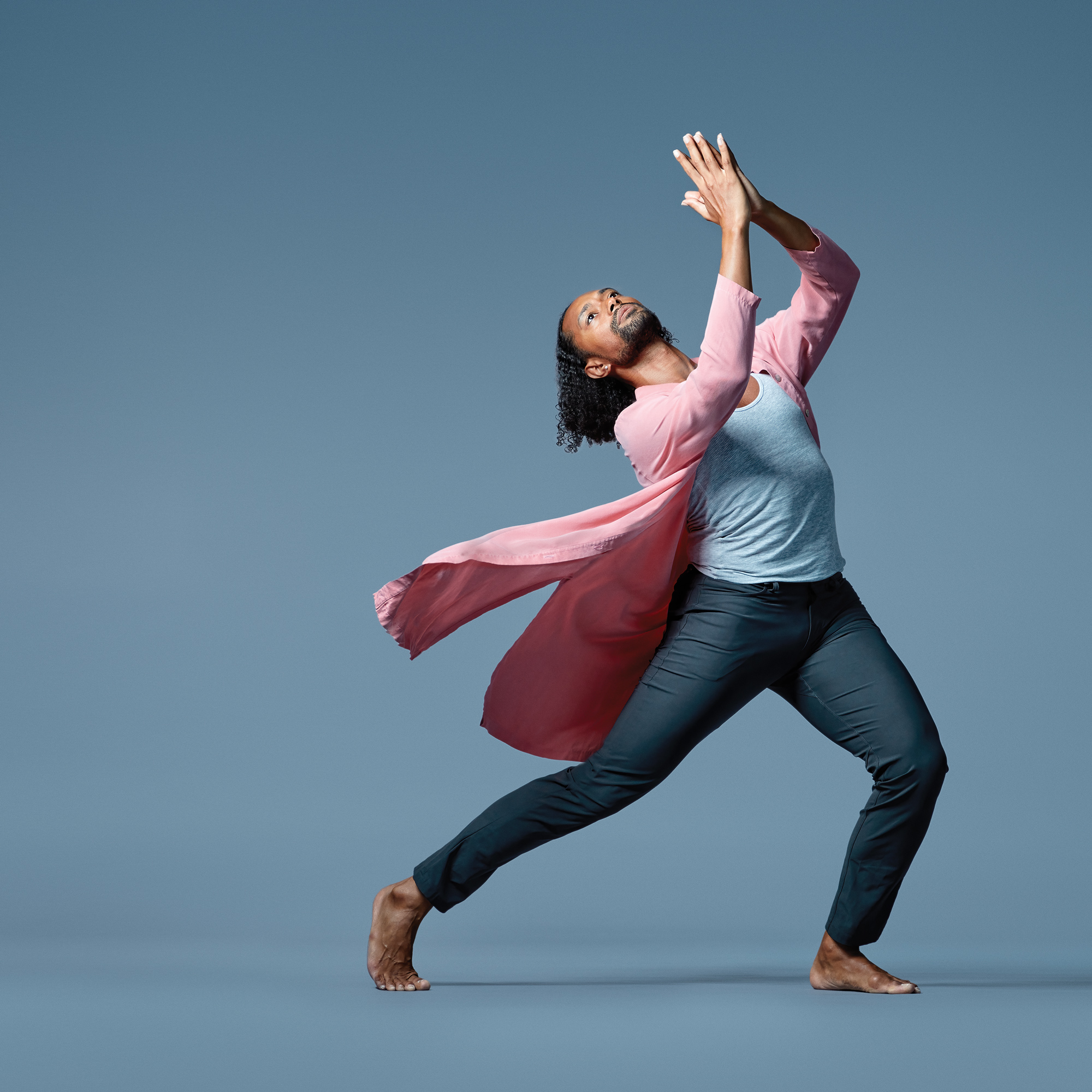 Dancer Abdiel Jacobsen poses wearing dark blue pants, a light blue tank top and a pink cardigan.