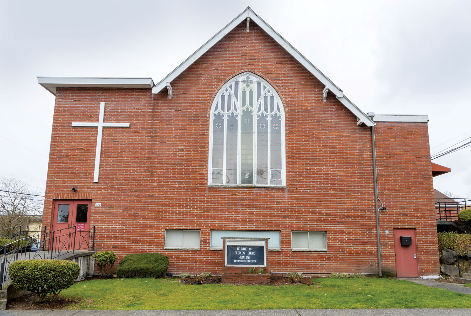 Red brick church building with a sign that says Welcome to Peoples Church