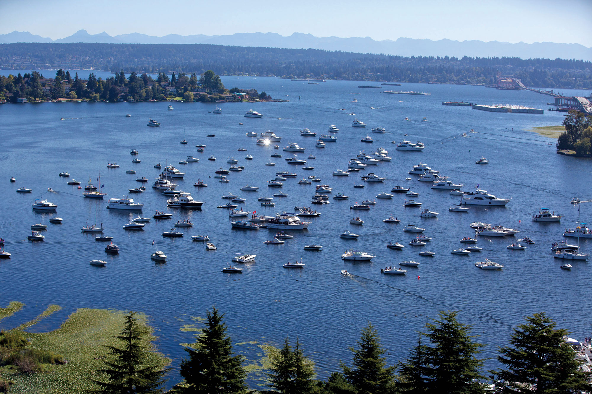 Dozens of boats gather on Lake Washington outside of Husky Stadium on a sunny day