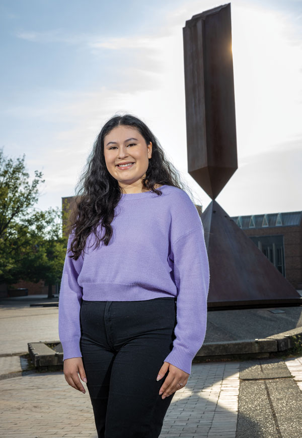 A smiling student in a purple sweater stands on Red Square