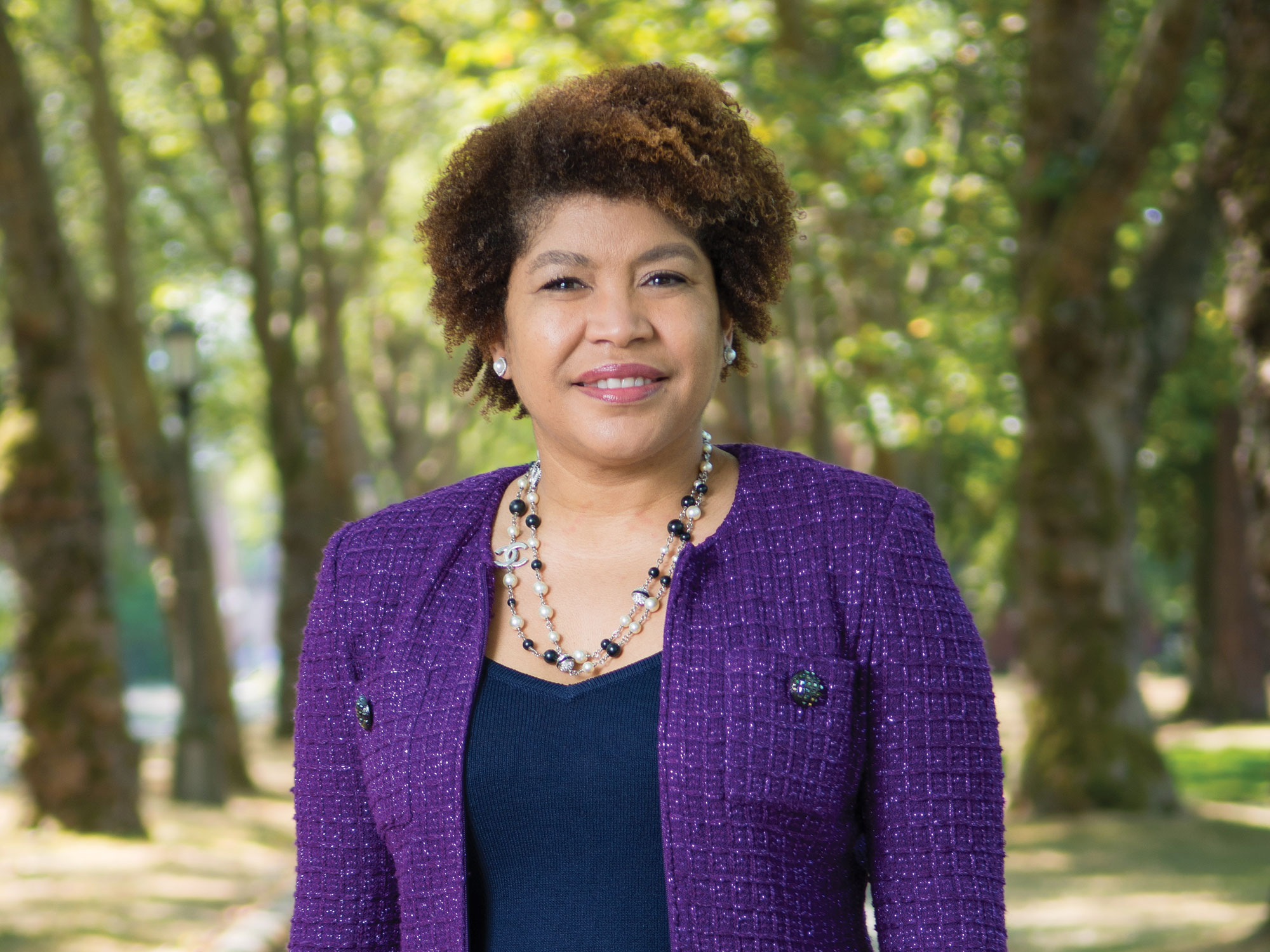A woman in a bright purple tweed jacket standing outside