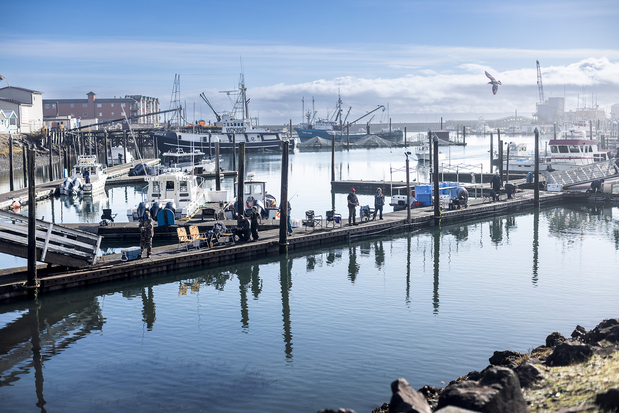 Several men stand fishing on a busy pier