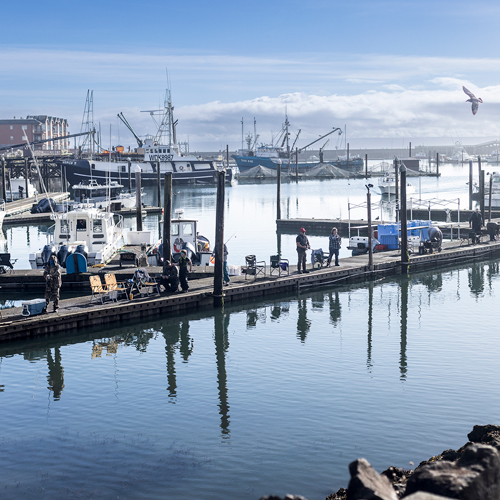 Several men stand fishing on a busy pier
