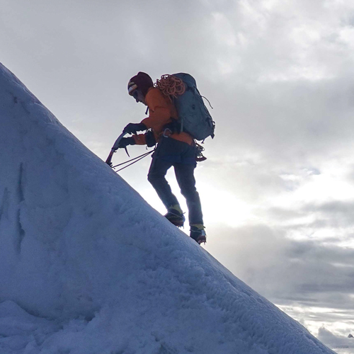 A man hikes a steep, snowy slope