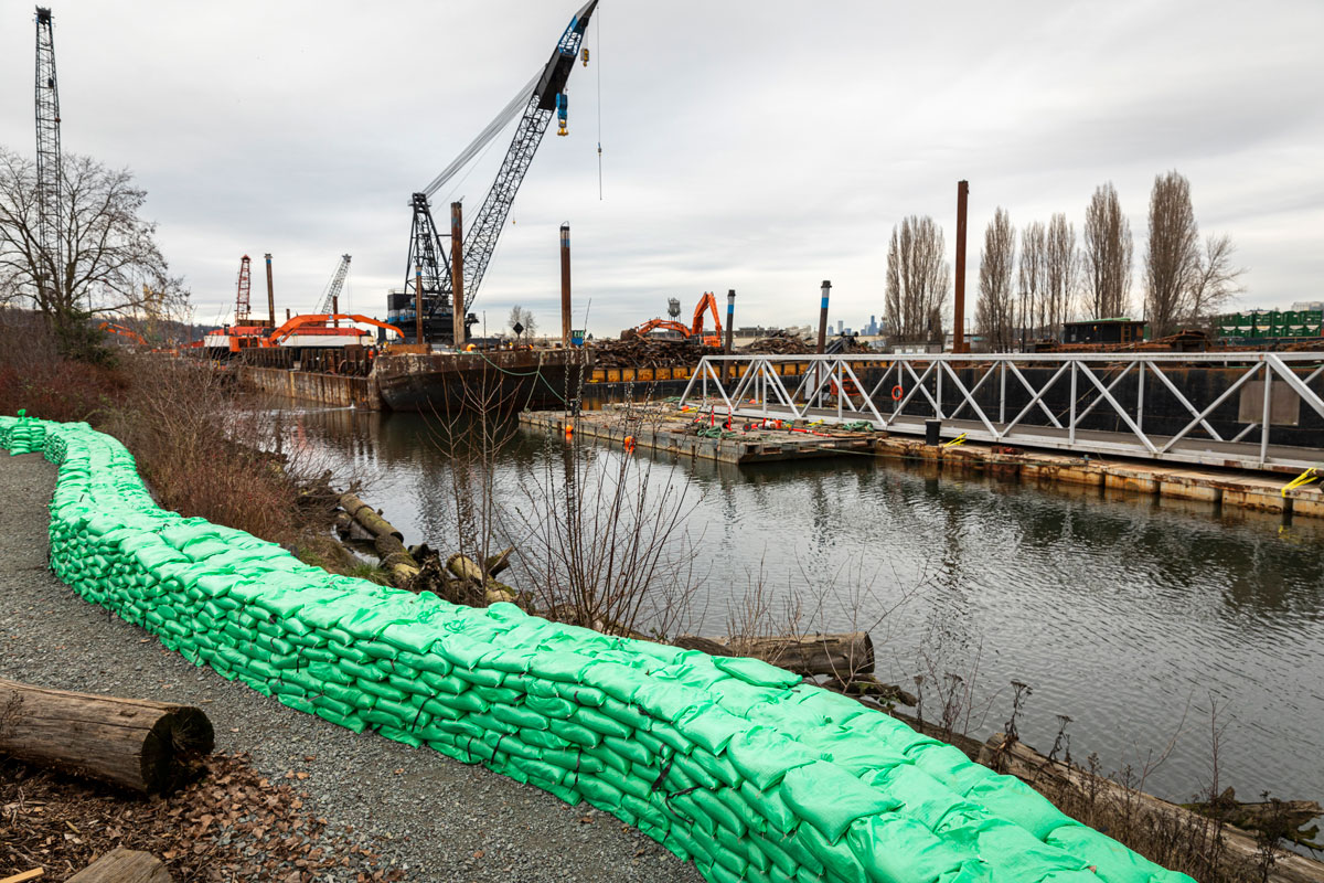 A sizable row of sandbags lines the riverbank of the Duwamish.