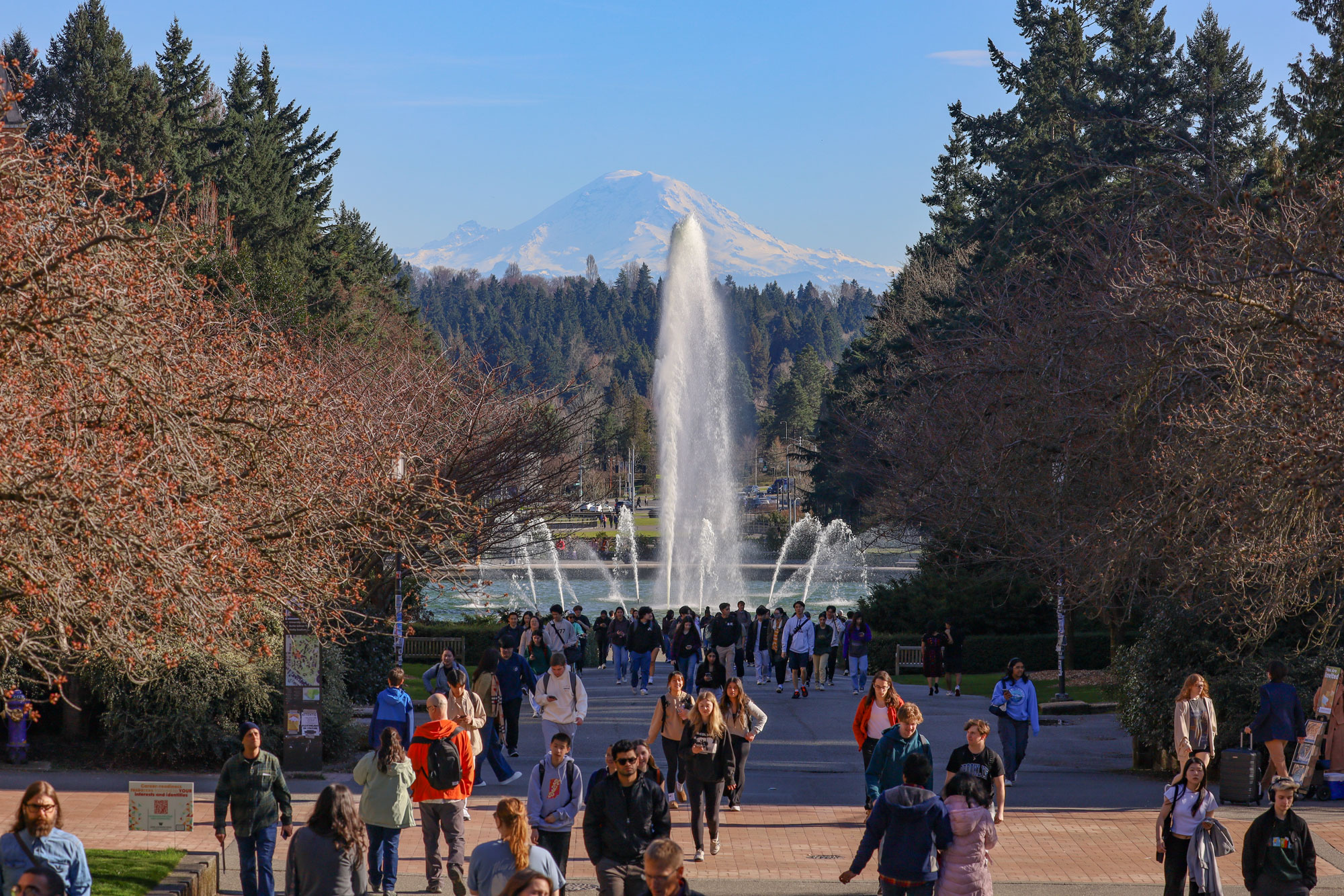 Students walk in front of Drumheller Fountain on the UW's campus, with Mount Rainier making a majestic appearance in the backkground.