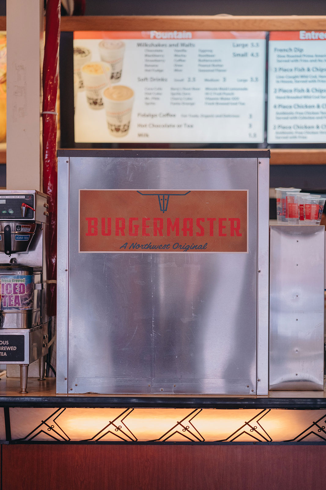 A closeup on a piece of machinery in the Burgermaster kitchen shows the logo with the slogan "A Northwest Original"