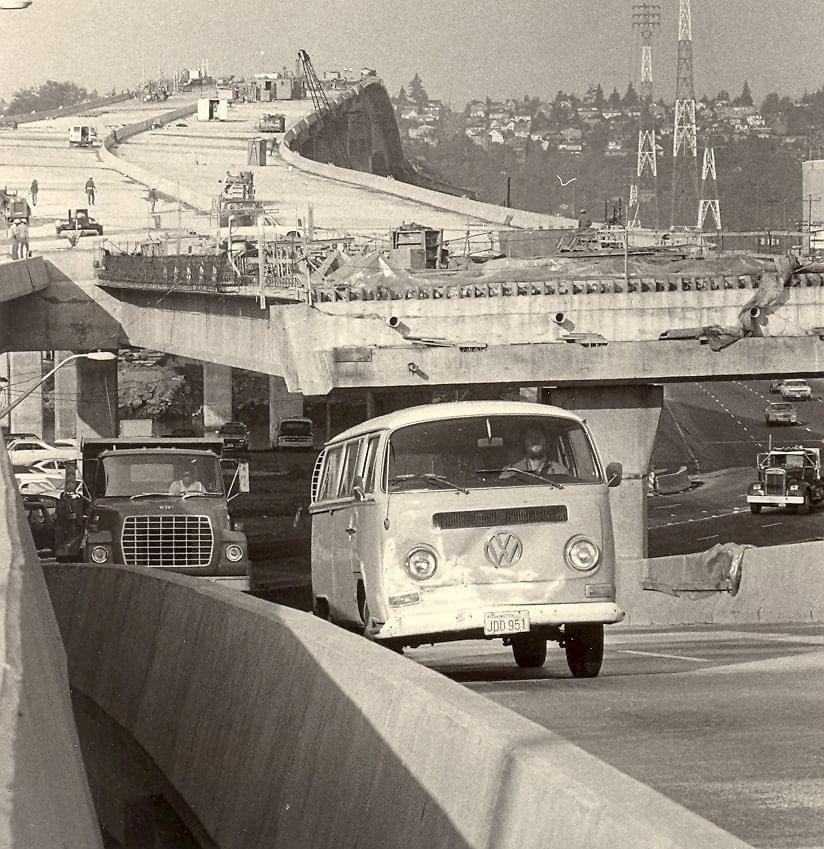 An old photo of the West Seattle Bridge shows a vintage VW bus and several semi trucks