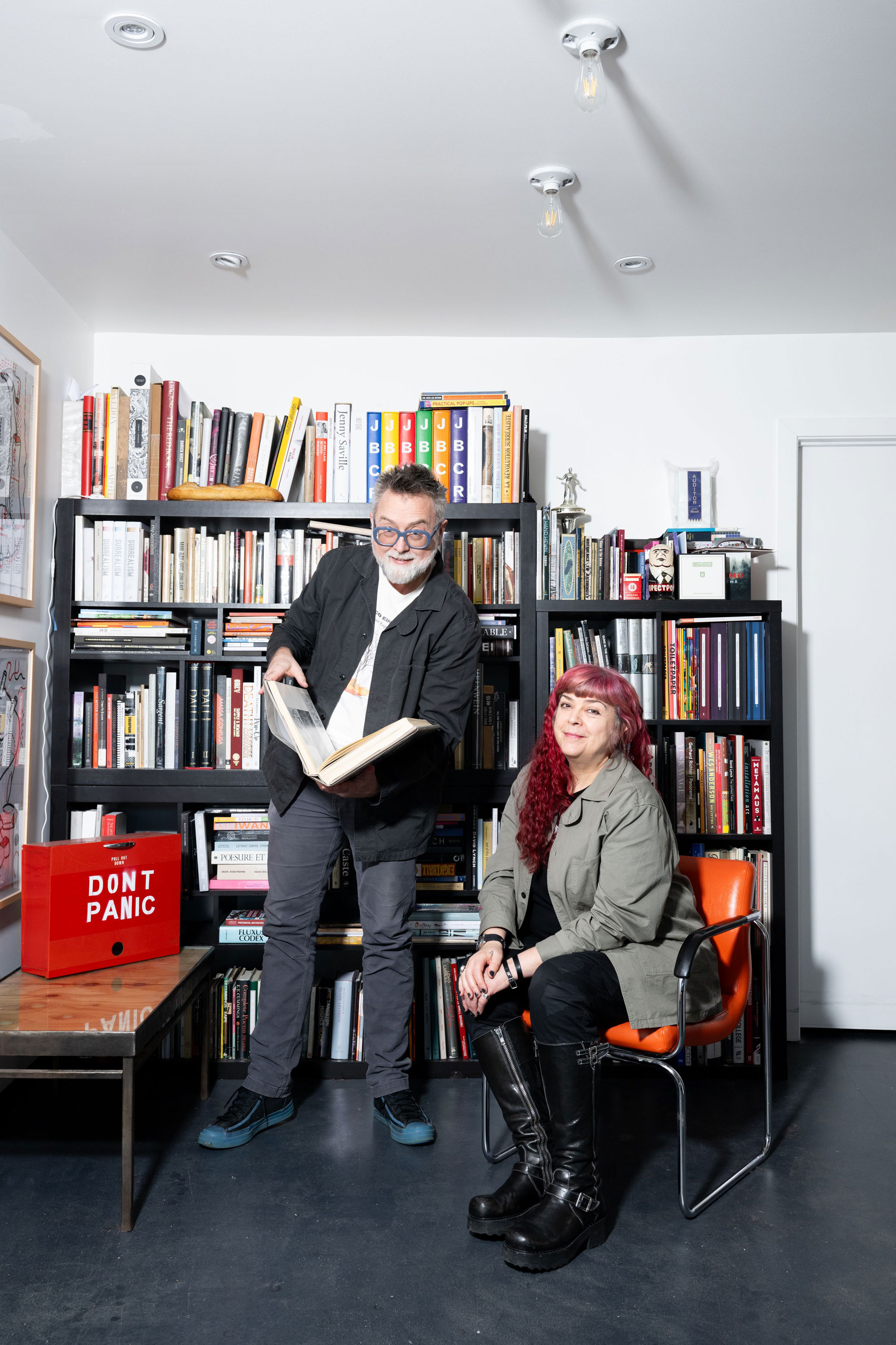 A man and woman smile in front of a bookshelf in their home