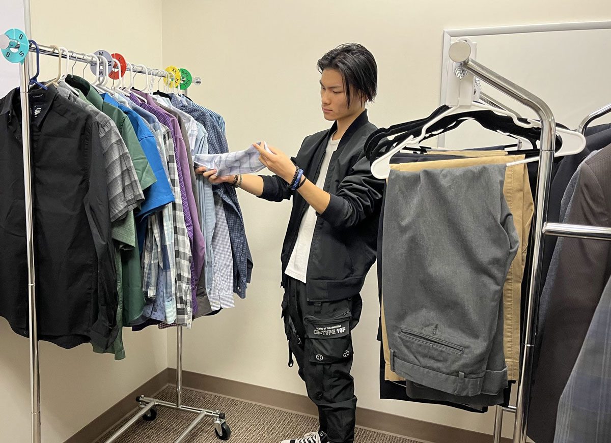 A student examines a rack of professional men's clothing.