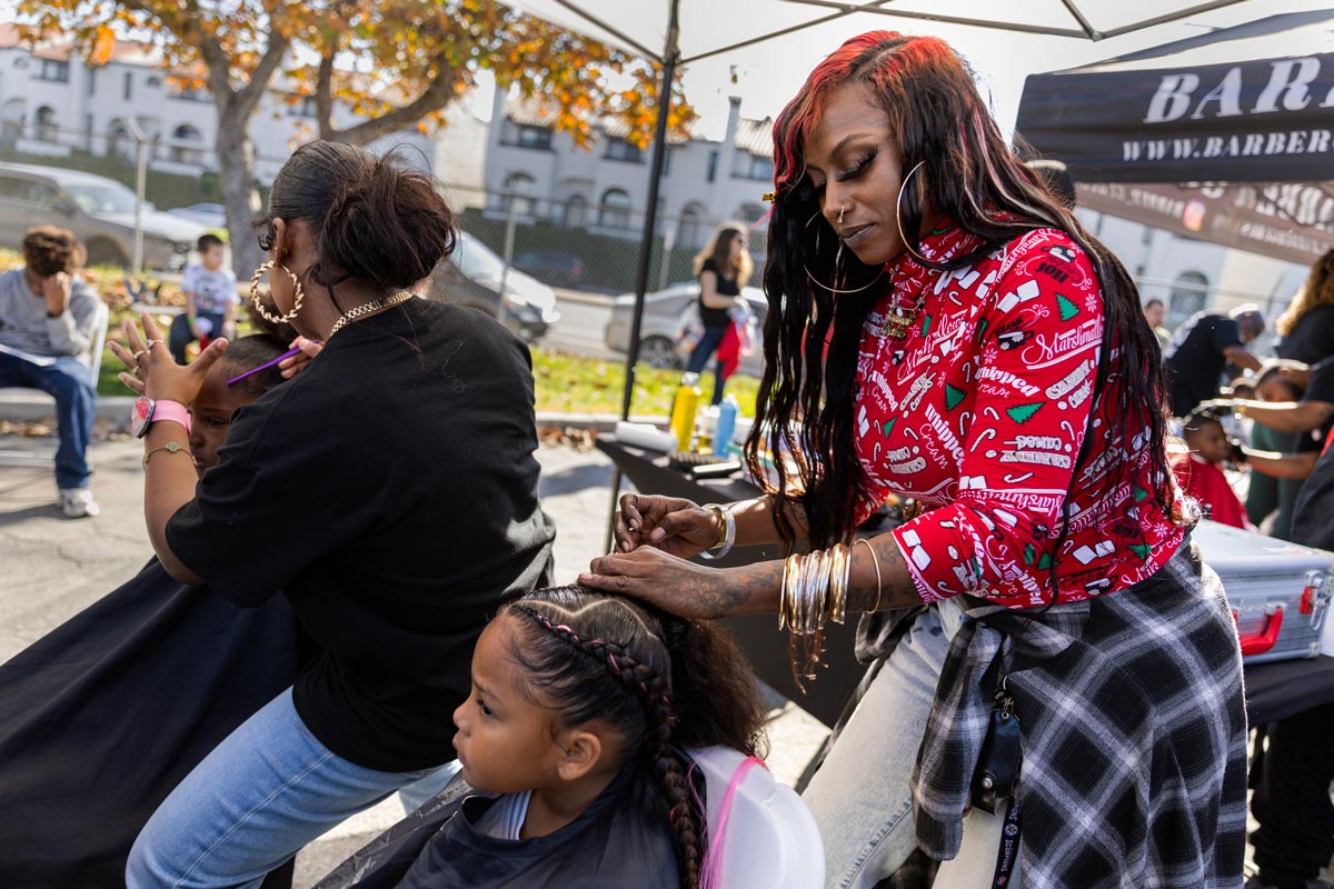 Two women braid two children's hair at a pop-up salon