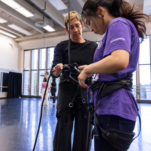 Rachael Lincoln helps a dance student adjust a harness
