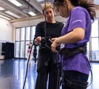 Rachael Lincoln helps a dance student adjust a harness