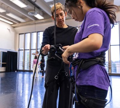 Rachael Lincoln helps a dance student adjust a harness
