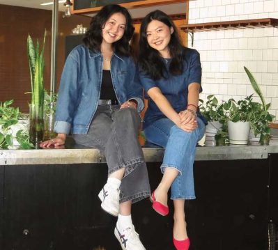 Lucy Kong and Krystal Graylin sit on the counter at Offline Coffee