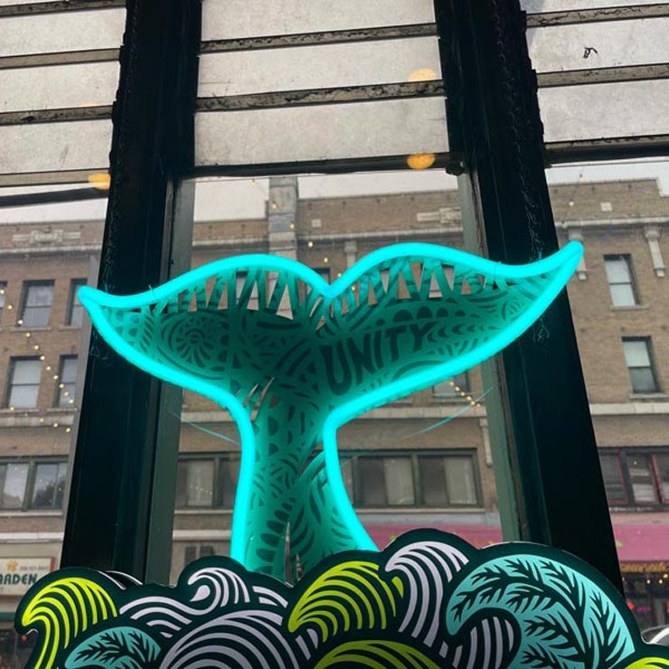 A neon-lit whale tail sculpture sits in the window of Tai Tung