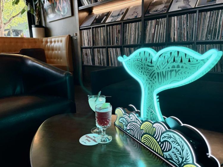 A neon-list whale tail sculpture sits next to two cocktails at Life on Mars