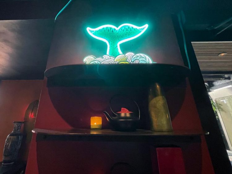 A neon-lit whale tail sculpture sits on a shelf at Tamarind Tree
